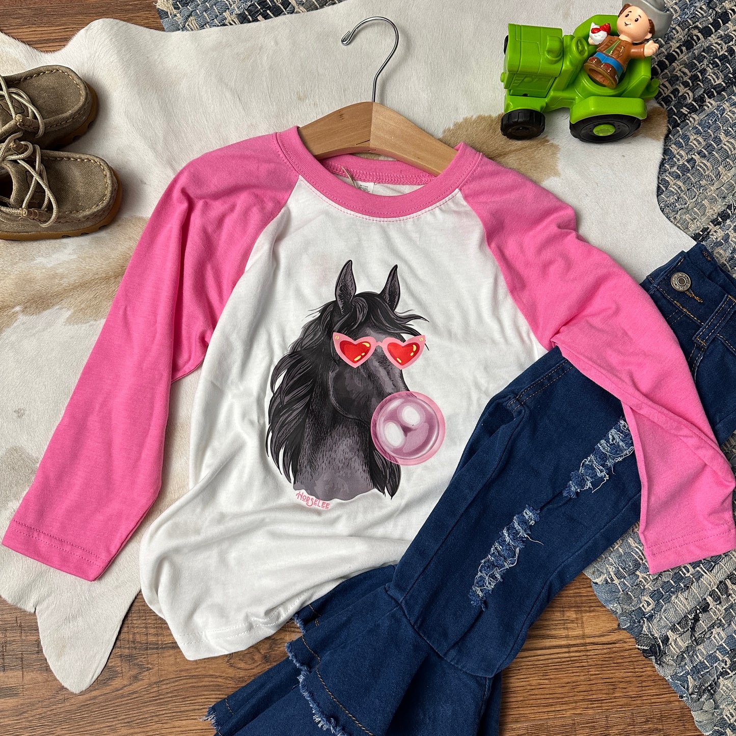 Pink baseball tee with printed horse pictured with sunglasses and a bubble gum bubble.