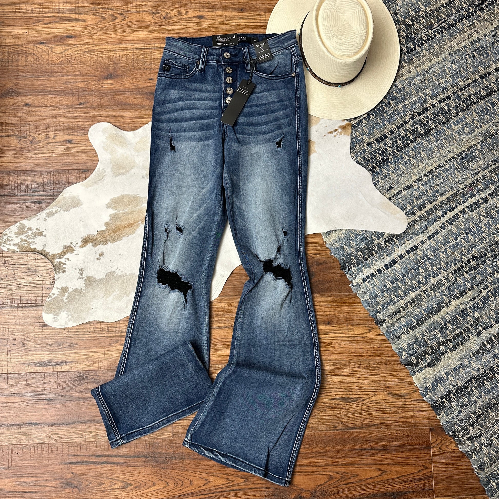 Acid wash button fly jeans with distressing at the knee.