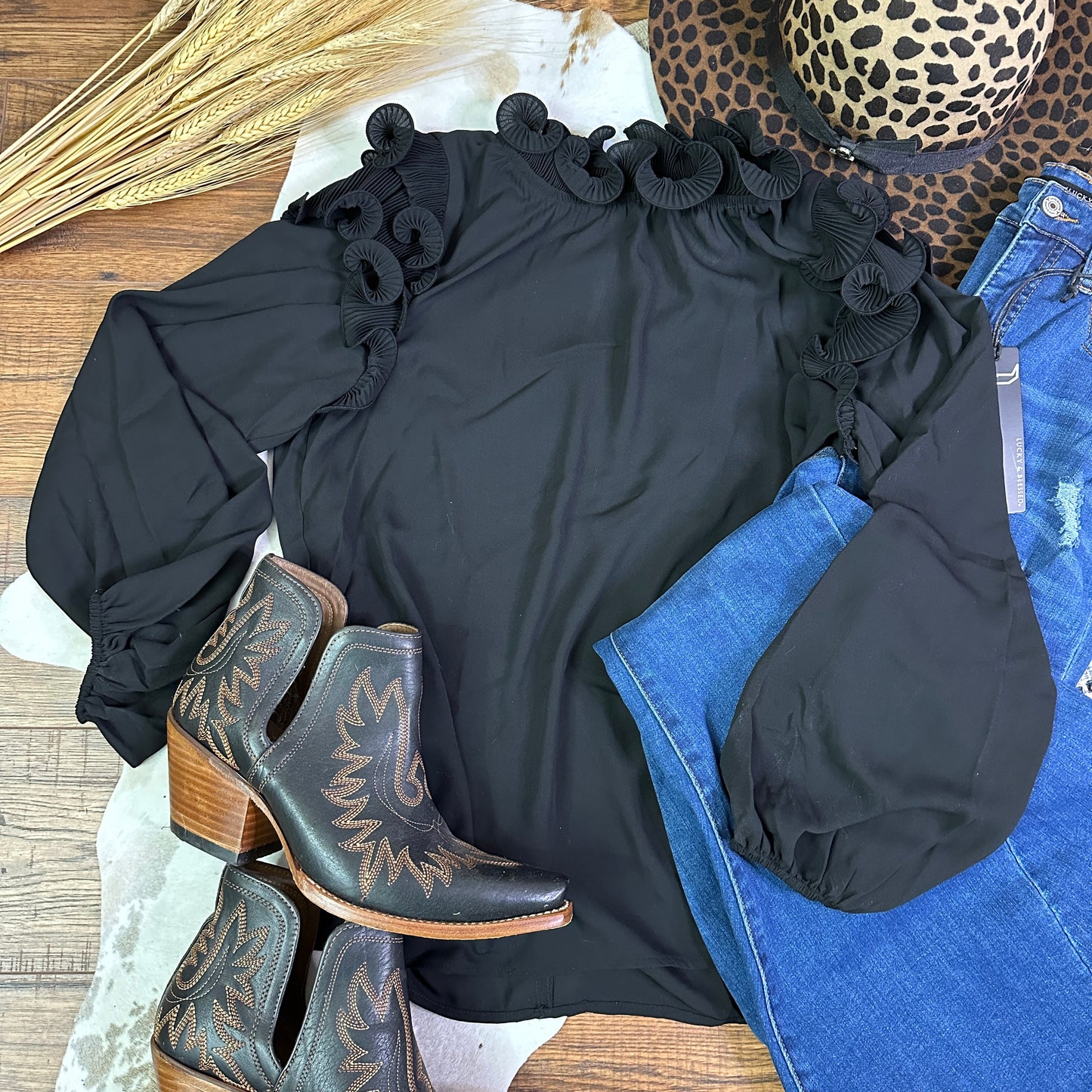 Black polyester top with ruffle details on neckline and shoulders.