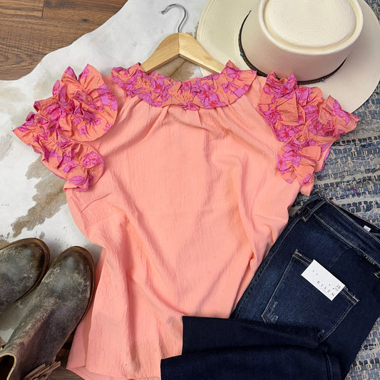 Coral pink top with coral and pink ruffle on neckline and sleeves.