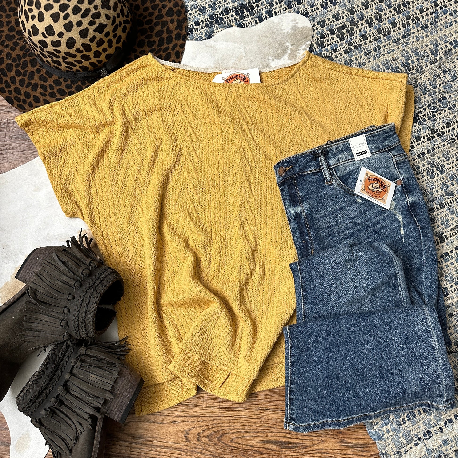 mustard colored short sleeve cable knit top with a high low hemline and side slits.