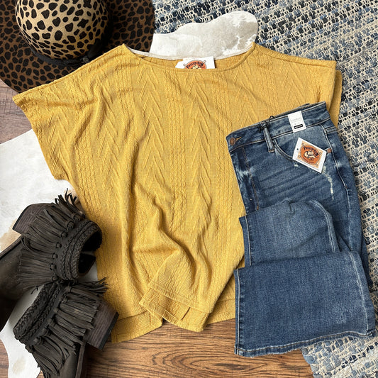 mustard colored short sleeve cable knit top with a high low hemline and side slits.