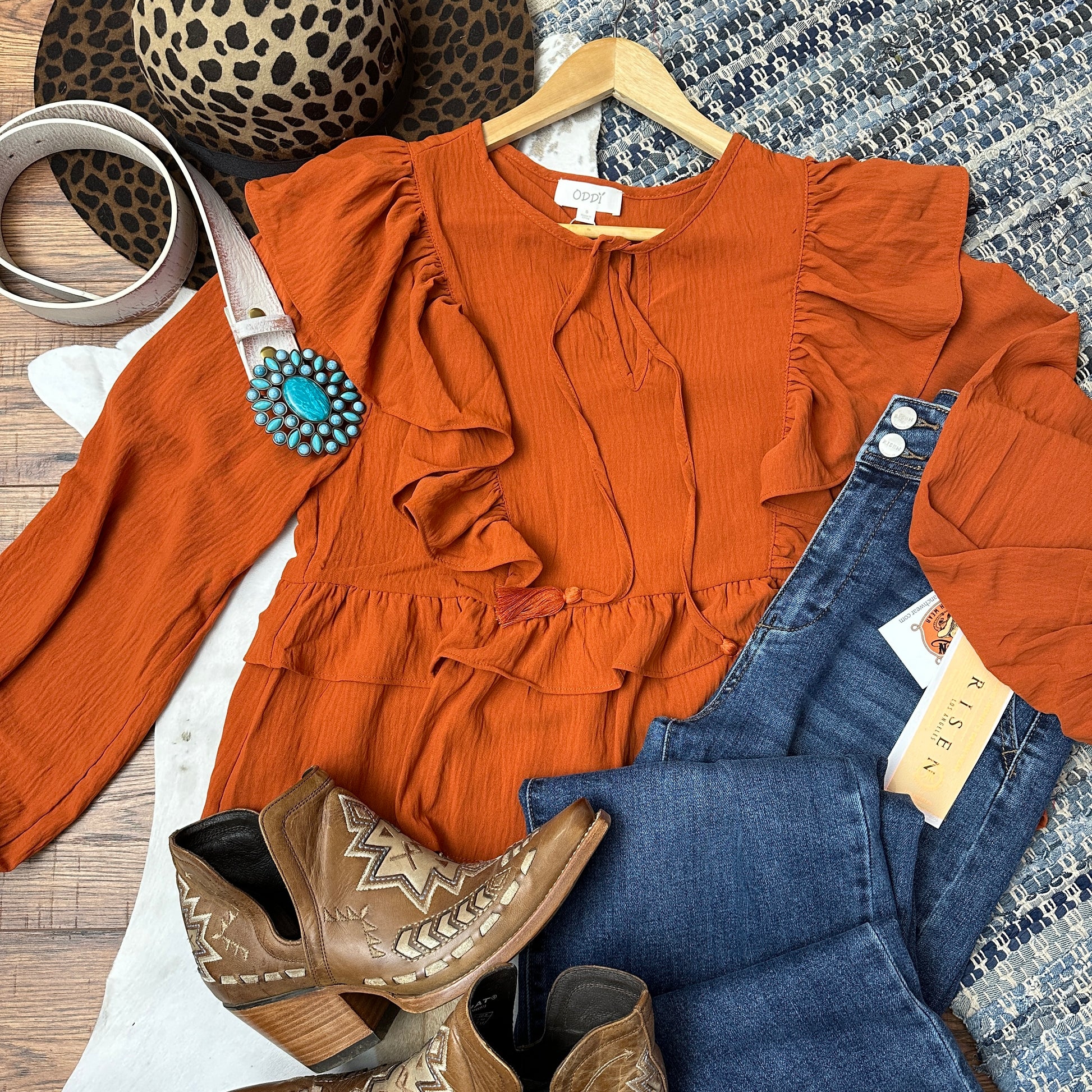 Burnt orange top with ruffles and tassel closure.