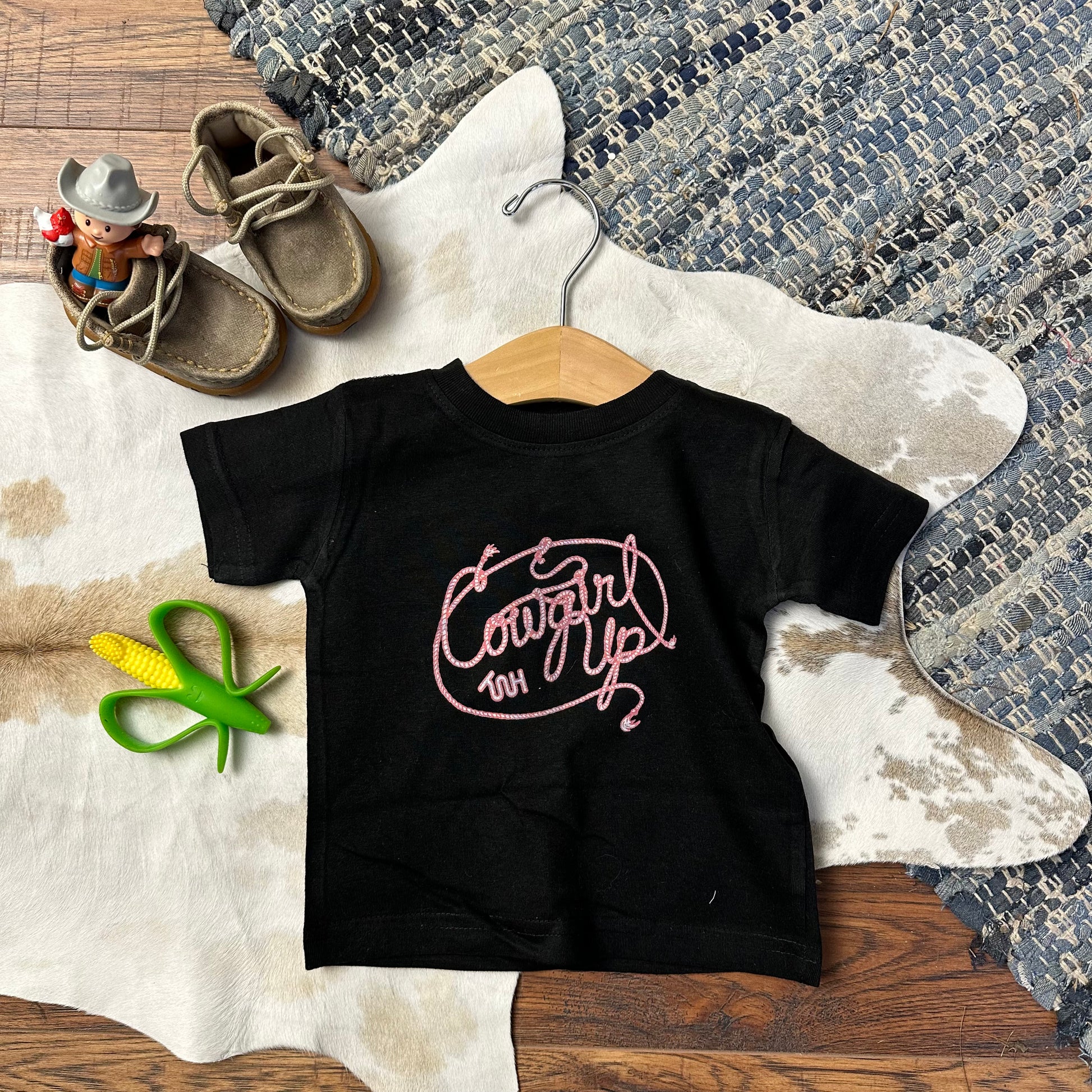 toddler and youth black tee that says Cowgirl Up in pink roped lettering