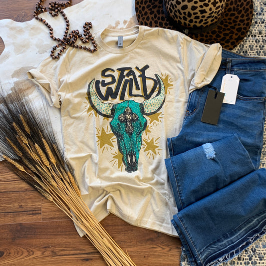 tan graphic tee with turquoise skull that says Stay Wild