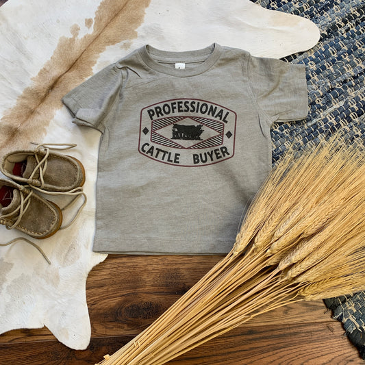 Gray tee with design that says Professional Cattle Buyer. Includes sillouhette of cattle.